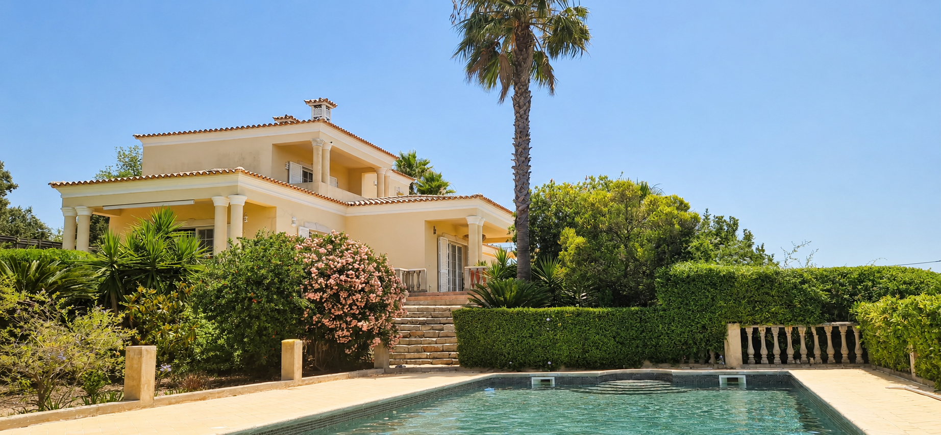 Casa Amani villa with pool, palm tree and Mediterranean garden under a clear Algarve sky